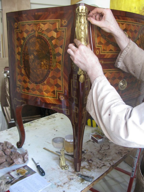 Réparation d’un meuble d’époque dans un atelier de restauration de meubles.